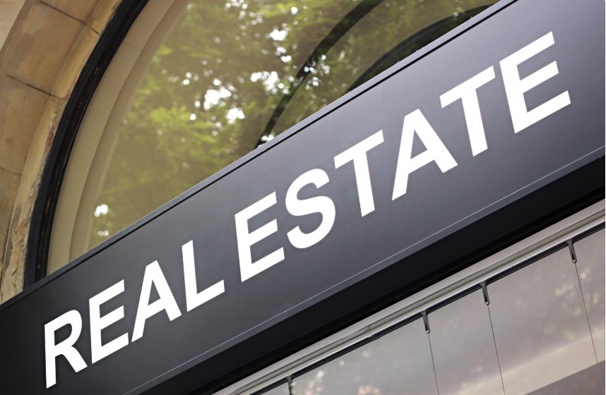 Rectangular Real Estate Sign on a Building. Sign has white lettering on a dark background